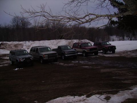 2000 Chevrolet Tahoe - A collection of SUVs and a pickup truck are parked in a lot with snow and mud visible.
