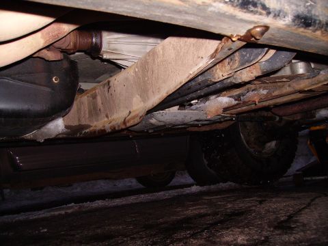 2000 Chevrolet Tahoe - A view of the undercarriage reveals the vehicle's frame, exhaust system, and tires, with some snow and ice present.