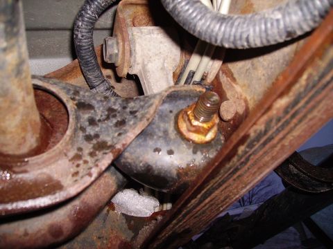 2000 Chevrolet Tahoe - Close-up of a heavily rusted vehicle suspension component with a bolt and wiring.