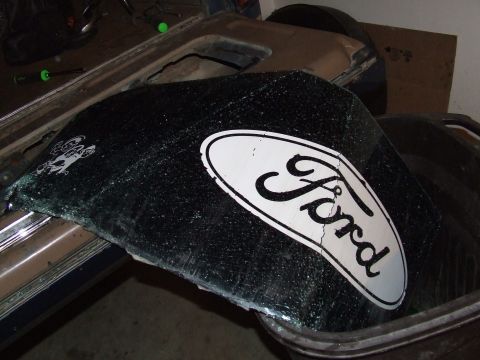 1986 Ford Bronco - The rear glass of a vehicle is broken and features a Ford logo.