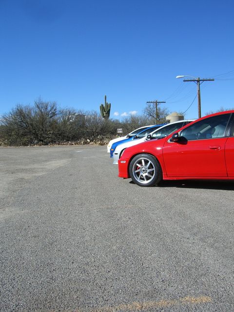 1996 Ford Probe - A red car is parked in a lot alongside two other vehicles, with a saguaro cactus visible in the background.