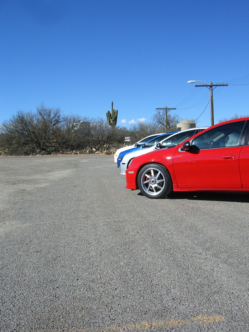 Red car parked next to a white and blue car under a clear blue sky