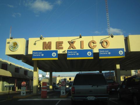 1990 Ford Bronco - Vehicles pass under a yellow MEXICO sign and blue Nada que Declarar lanes at a Mexican border crossing.