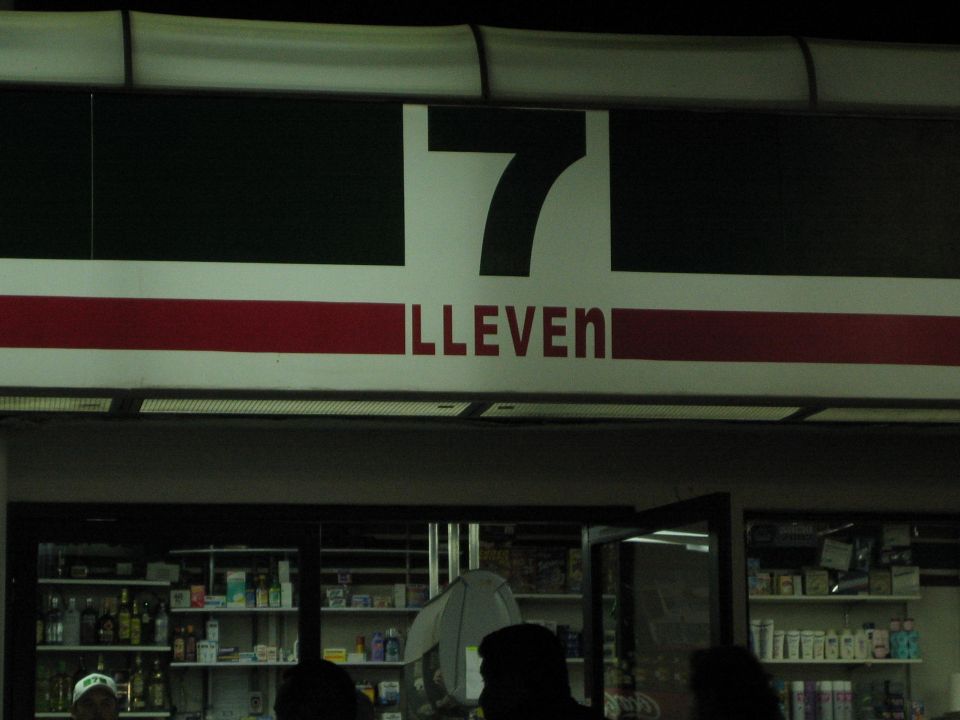 Dim 7-Eleven storefront sign above a convenience store counter