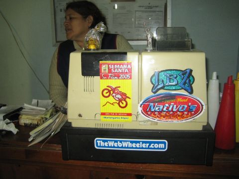 1990 Ford Bronco - woman sits behind a counter next to a beige printer covered in racing stickers and a TheWebWheeler.com decal.