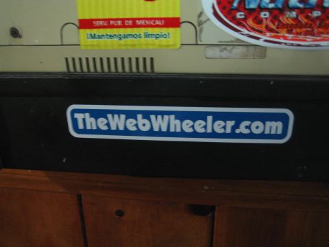 1990 Ford Bronco - blue TheWebWheeler.com sticker is affixed to a black equipment housing below racing stickers.