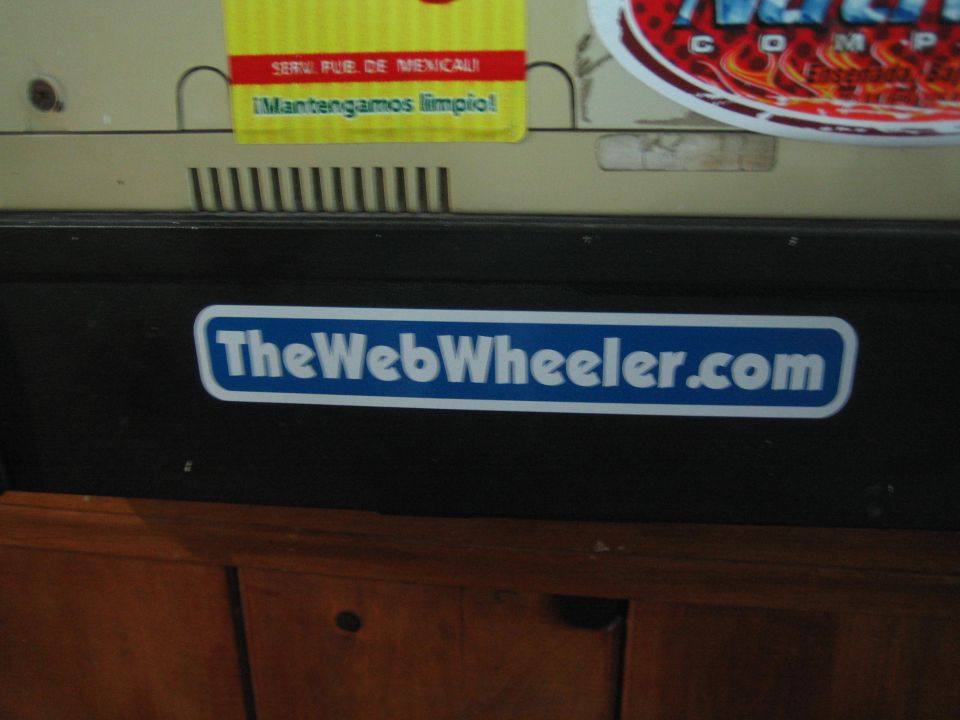 Close-up of TheWebWheeler.com blue decal on a black equipment stand