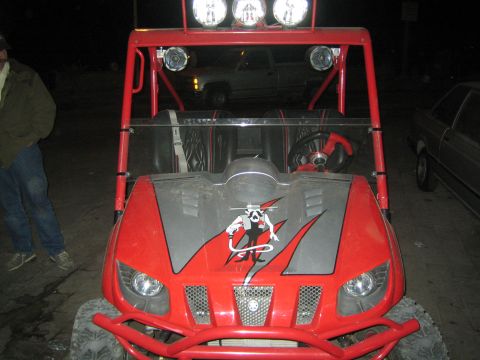 1990 Ford Bronco - red Yamaha UTV with overhead lights and a gunslinger hood graphic faces the camera as a person stands nearby.