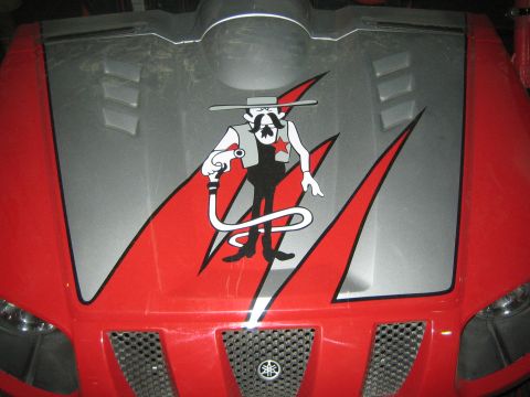 1990 Ford Bronco - Detail of a red UTV hood showing a gray bandit gunslinger graphic above the Yamaha tuning-fork emblem.