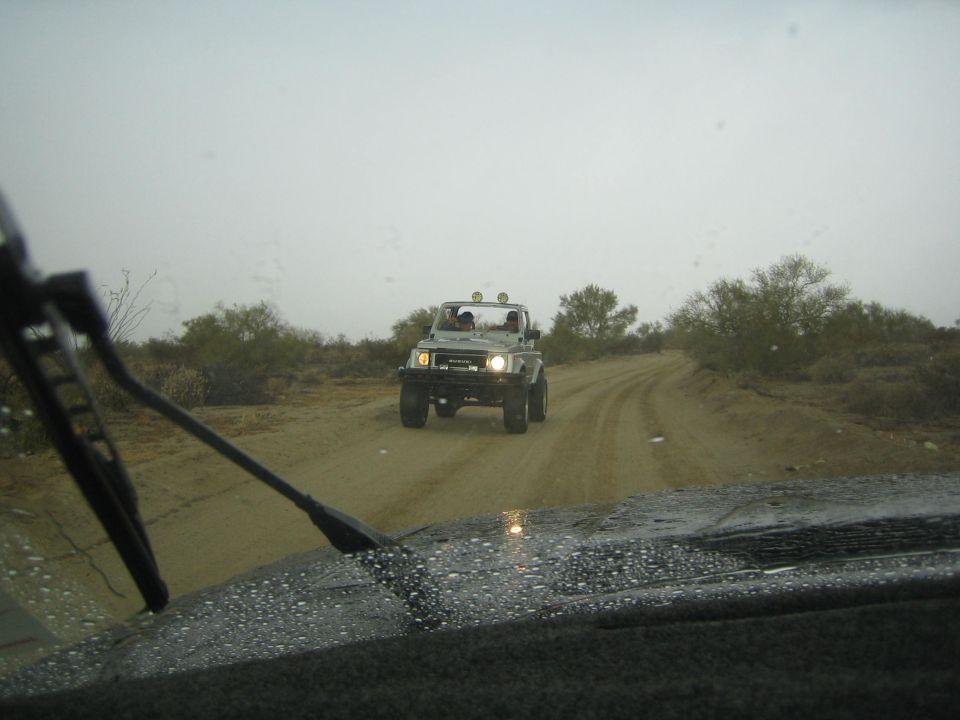 White off-road buggy with light bar driving toward camera on a desert dirt road