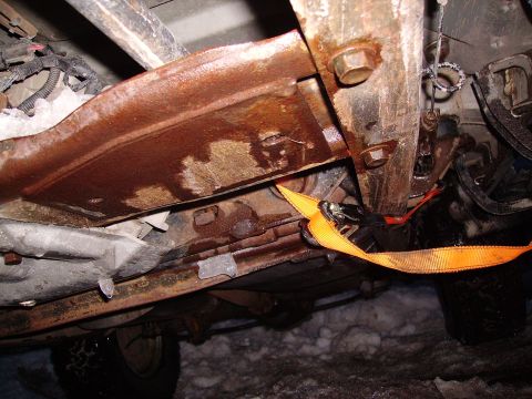 2000 Chevrolet Tahoe - Underbody view of a rusty vehicle, showing frame and an orange strap. Snow is visible on the ground.