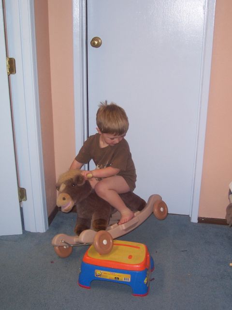 1981 Ford F-150 - A young child sits on a toy rocking horse in a room with blue carpet and white doors.