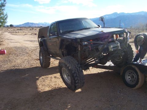 1981 Ford F-150 - Custom off-road truck with extensive modifications, including a roll cage and winch, loaded onto a trailer.