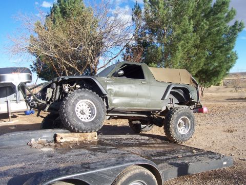 1981 Ford F-150 - Modified off-road truck with large tires and a custom front end is loaded onto a trailer.