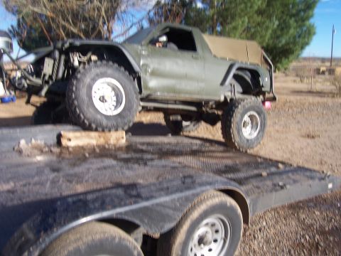 1981 Ford F-150 - This heavily modified off-road truck features oversized tires and a custom front end, seen loaded onto a trailer.
