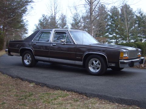 1982 Ford Crown Victoria LTD - This sedan, likely from the early 1980s, features a dark brown finish, extensive chrome trim, and aftermarket Cragar SS wheels.