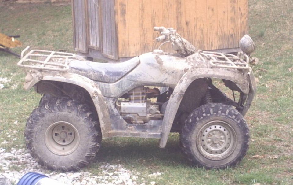 muddy ATV parked next to a wooden structure