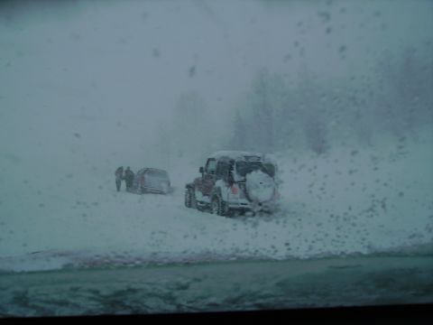 2000 Chevrolet Tahoe - Two SUVs are seen in a snowy landscape with people standing near one of them.