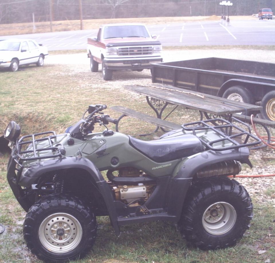Green Honda Rancher ATV with front and rear racks parked on grass