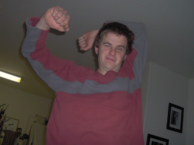 Man in a red and grey striped long-sleeve shirt flexing his bicep