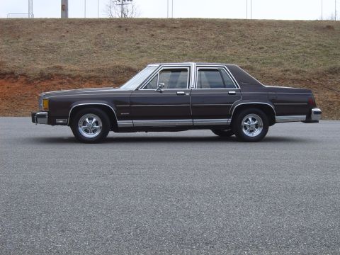 1982 Ford Crown Victoria LTD - A dark brown Ford sedan with aftermarket wheels is shown from the side against a neutral background.