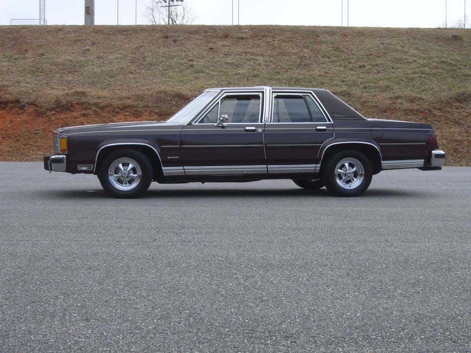 Brown Ford LTD Crown Victoria sedan in profile parked on pavement