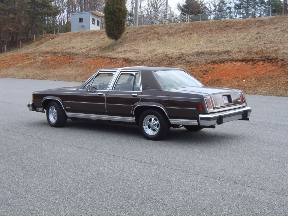 Dark brown Ford LTD Crown Victoria sedan, rear three-quarter view on asphalt