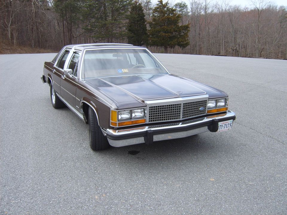Brown 1980s Ford sedan with chrome grille and Cragar wheels parked on asphalt