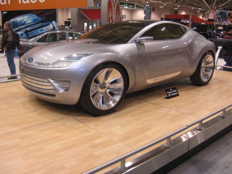 1999 Ford Crown Victoria - A silver concept car, identified by "REFLEX" badging, is displayed on a wooden platform at an auto show.