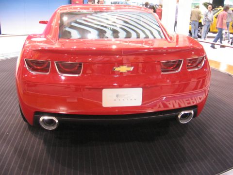 1999 Ford Crown Victoria - Red Chevrolet Camaro concept car displayed at an auto show, rear view.