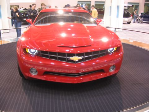 1999 Ford Crown Victoria - A red Chevrolet Camaro is showcased on a rotating platform at an auto show.