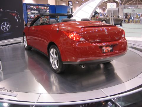 1999 Ford Crown Victoria - A red convertible is displayed on a rotating platform at an auto show.