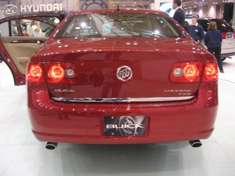 1999 Ford Crown Victoria - Rear view of a red Buick Lucerne CXS at an auto show with the doors open.