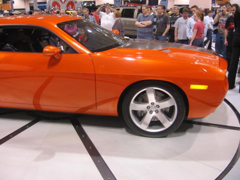 1999 Ford Crown Victoria - Orange sports car on display at an auto show with spectators in the background.