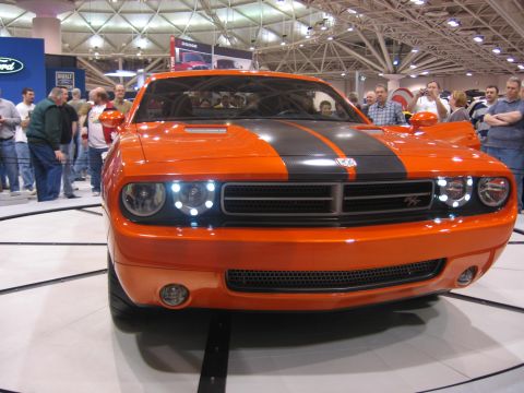 1999 Ford Crown Victoria - This orange Dodge Challenger is on display at an auto show with people in the background.
