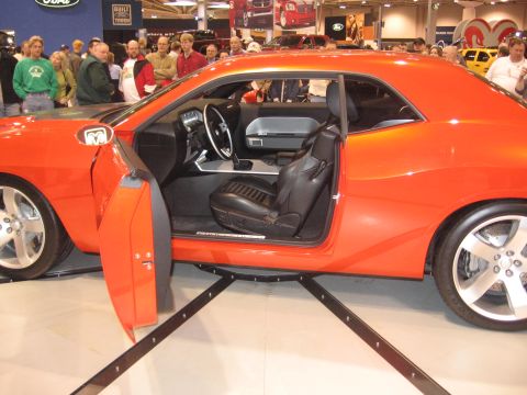 1999 Ford Crown Victoria - Interior view of an orange muscle car, black leather seats and a modern dashboard, displayed at an auto show.