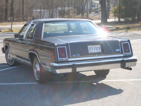 1982 Ford Crown Victoria LTD - The rear of a dark-colored sedan is shown parked in a lot, with a Virginia license plate visible.
