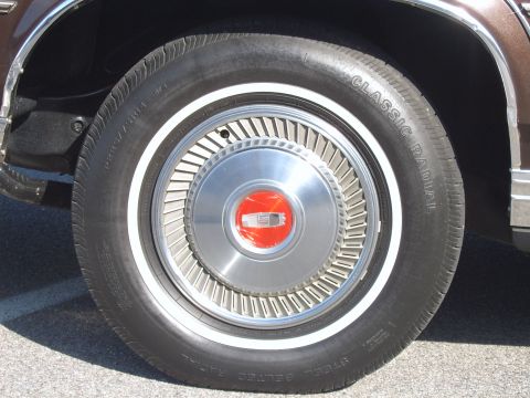 1982 Ford Crown Victoria LTD - Close-up of a 1982 Ford Crown Victoria LTD wheel with a distinctive chrome hubcap and red emblem.
