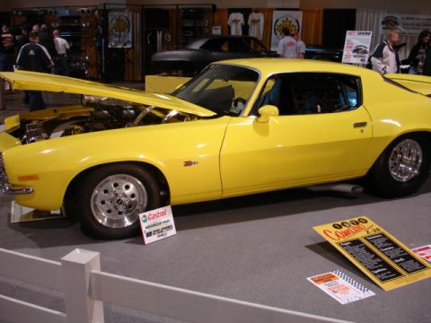 1981 Ford Mustang - A yellow coupe is displayed with its hood open, revealing the engine and chrome wheels.