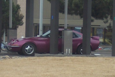 1972 Ford Ranchero - Purple coupe with pop-up headlights and a spoiler is parked near pillars.