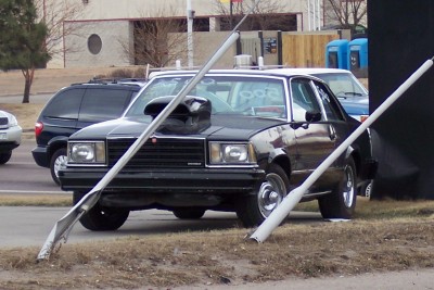 1972 Ford Ranchero - A modified black sedan with a prominent hood scoop is parked on the side of the road.