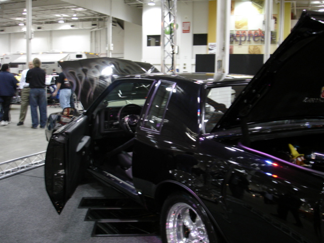 black coupe with custom flames on hood, doors open, interior visible