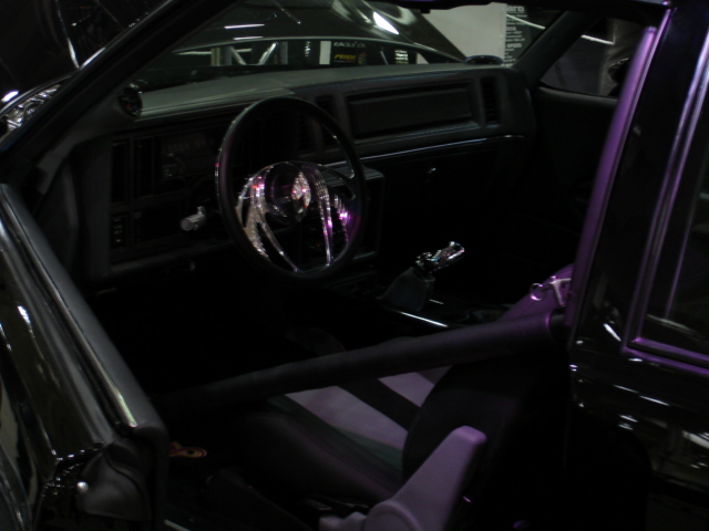 car interior showing steering wheel, dashboard, roll cage, and racing seats