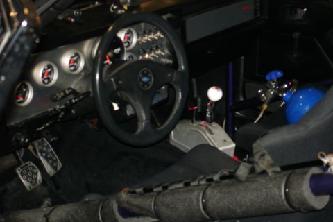 1981 Ford Mustang - The interior of a modified car features racing gauges, a custom shifter, and a nitrous oxide tank.