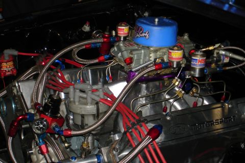 1981 Ford Mustang - Close-up view of a modified engine bay with various aftermarket parts and braided hoses.