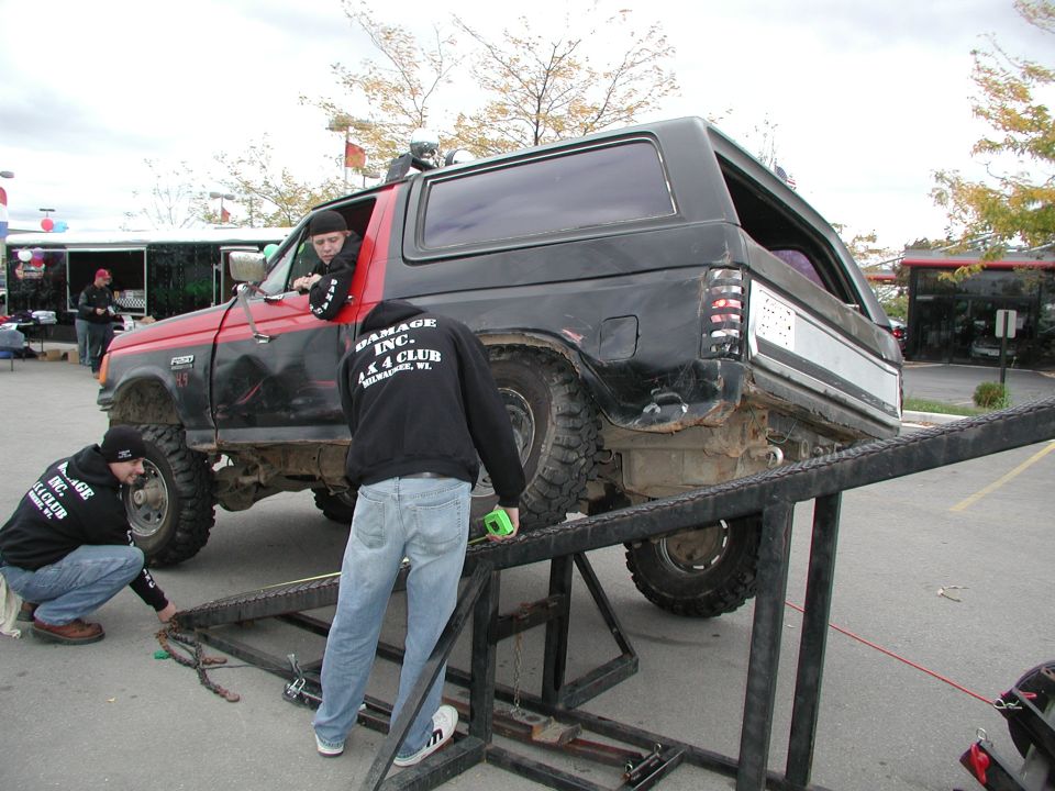Black and red Ford Bronco on a ramp, with people working on it