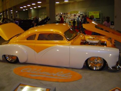 1979 Ford Bronco - A customized coupe with an orange and white paint scheme is displayed with its hood and trunk open.