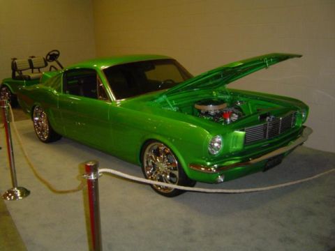 1979 Ford Bronco - A bright green custom car is displayed indoors with its hood open, revealing the engine compartment.