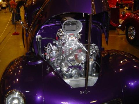 1979 Ford Bronco - A custom purple hot rod is displayed with its hood open, revealing a polished engine and supercharger. Another vehicle is visible in the ba…