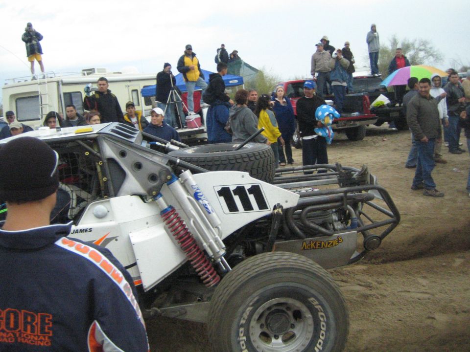 Rear of off-road race buggy number 111 with exposed roll cage and shocks